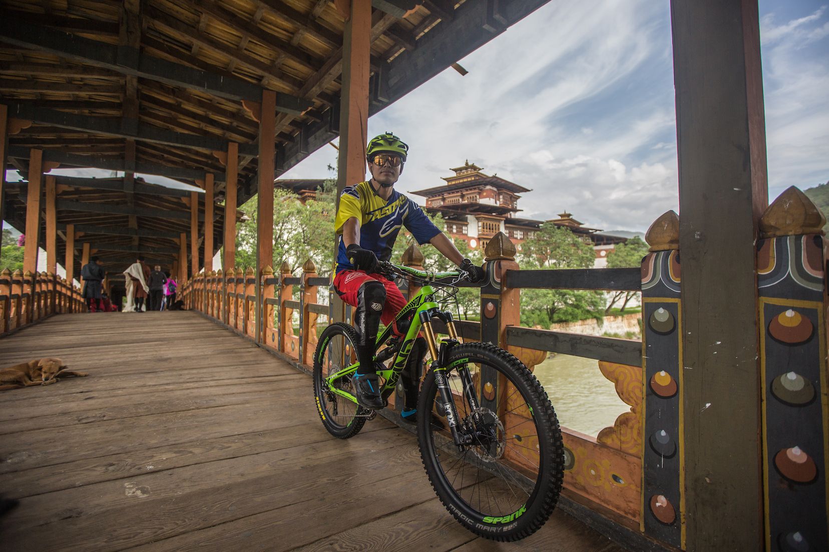 A traditional cantilever bridge leads across the river to a Bhutanese dzong