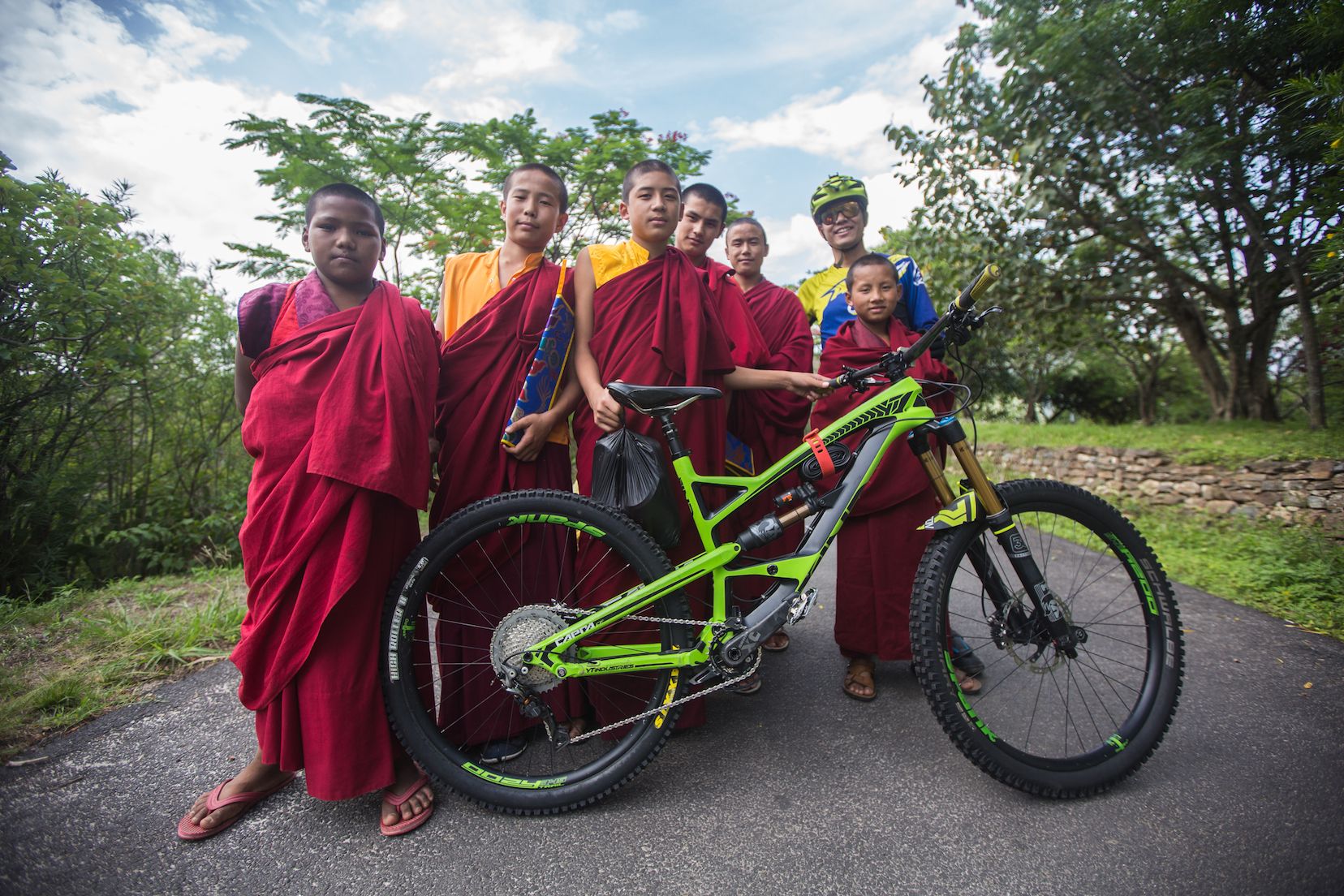 Young monks in red robes gather around a mountain bike outside a monastery in Bhutan