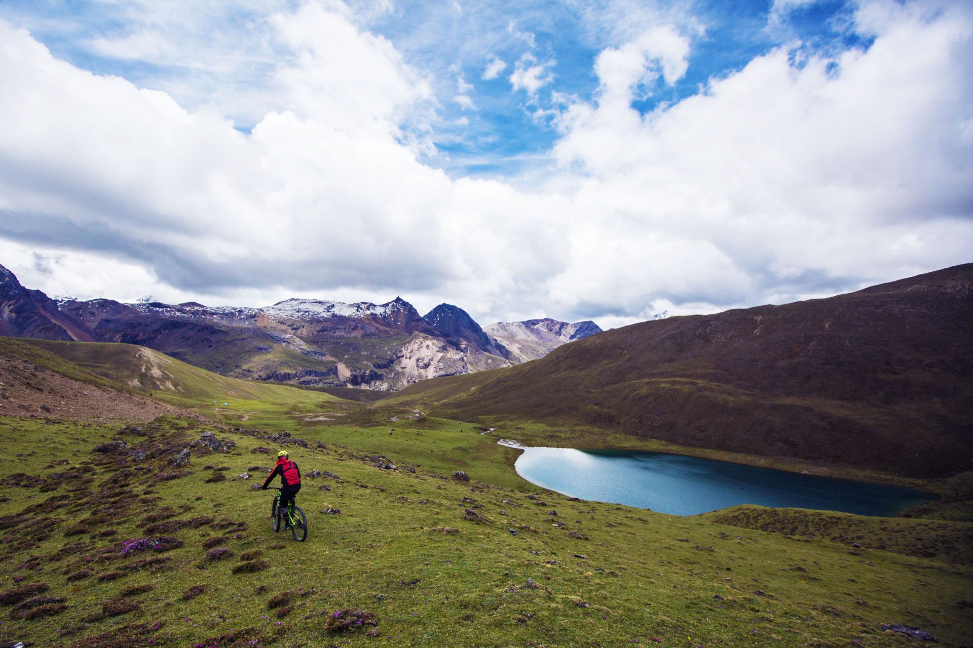 Riders skirt the shore of a high alpine lake beneath Yele La pass