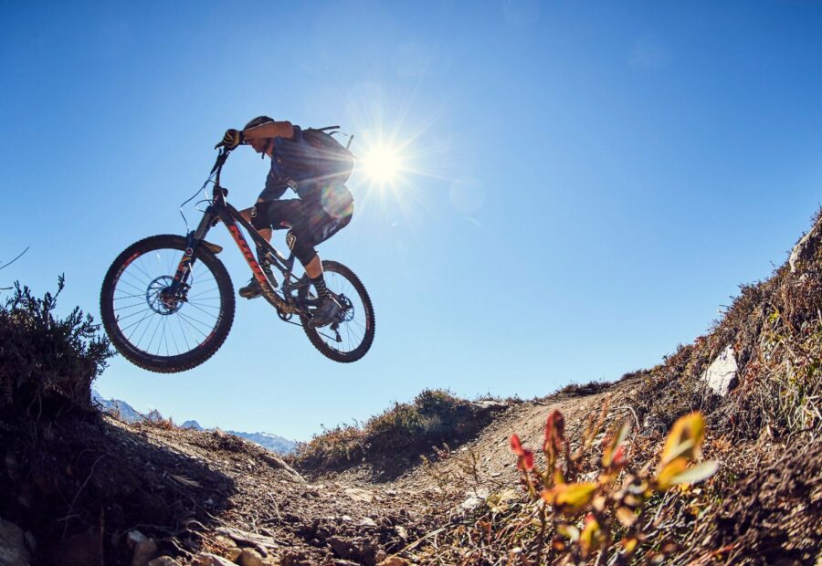 A rider silhouetted against the sun mid-jump